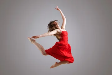 Gordijnen elegant female dancer in red dress jumping in the air © mimagephotos