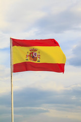 Spain flag on a blue sky with clouds background