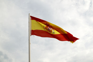 Spain flag on a blue sky with clouds background
