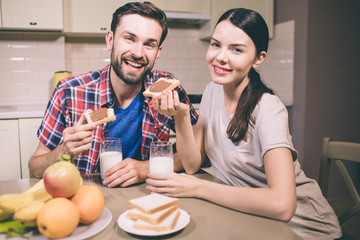 Positive picture of guy and girl sits together at tble and smiling. They look on camera. People...