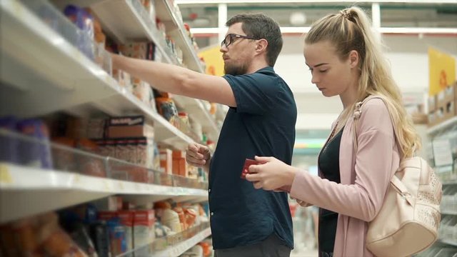 Couple buying food on weekends in supermarket. Family buying nutritional food for breakfast, different boxes of oatmeal and cereal.