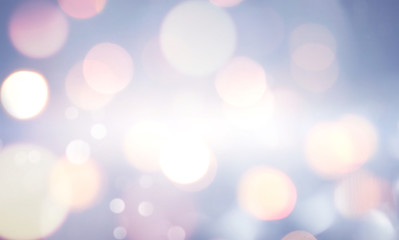 Winter blurry background in light blue pink tones. Christmas lights defocused with beautiful light, abstract snowflakes in blur, copy space.