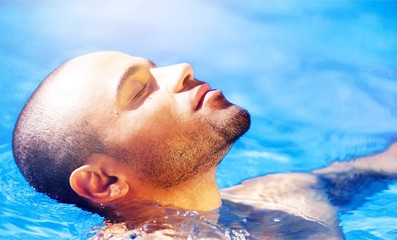 Photo of muscular Man relax in blue water of Swimming Pool.