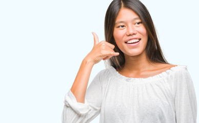 Young asian woman over isolated background smiling doing phone gesture with hand and fingers like talking on the telephone. Communicating concepts.