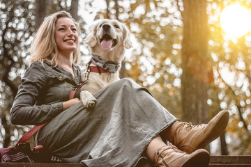 Enjoying resting.Portrait of beautiful smiling woman with dog in the park.