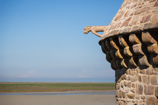 A Gargoyle Along a Roof in Mont Saint Michel Looks Over the Quick Sand of the Bay with Copy Space