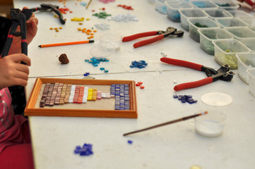 The child makes a panel of colored glass mosaic. Tools for creativity.