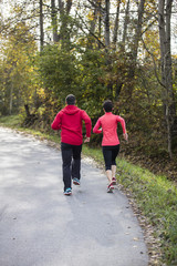 Fototapeta premium Young couple running on the sunny day in the autumn forest of the Bavarian National Park, Bavaria, Germany