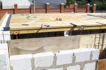 view of the wooden formwork with metal holders, which will be filled with the overlap between the floors in the country house under construction from the foam block