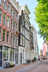 Zabytkowe kamienice amsterdamskie wśród drzew w słoneczny dzień. © W Korczewski