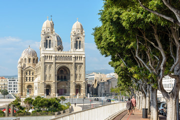 The cathedral of Sainte-Marie-Majeure, known as La Major, the byzantine-style cathedral of Marseille, France, achieved in 1893 in the district of La Joliette with a couple strolling under the trees.