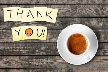 Coffee cup and thank you note   on wooden background