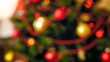 Fototapeta na wymiar Out of focus image of red and golden baubles hanging on Christmas tree at living room