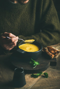 Man In Dark Winter Sweater Eating Sweet Corn And Shrimp Chowder Soup From Bowl. Autumn Or Winter Warming Food