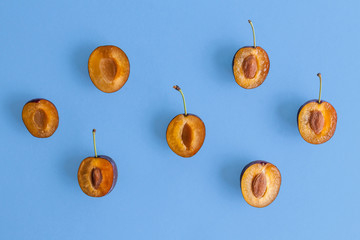 Halves of fresh, juicy, ripe plums on a blue background. Fresh fruit