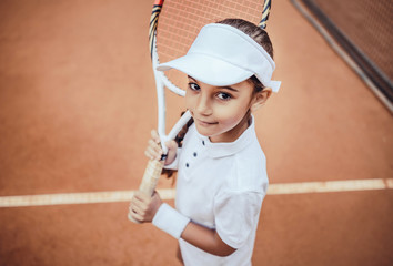 Tennis is my favorite game! Portrait of a pretty sporty child with a tennis racket. Little girl...