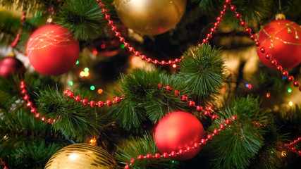 Closeup photo of Christmas tree branches with hanging colorful baubles