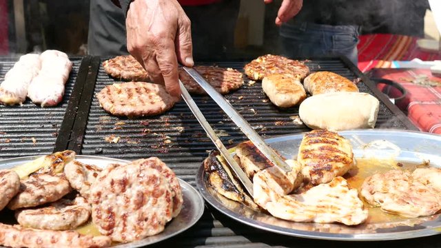 Cooking meat dishes on a big grill table on street food festival - Balkan cuisine