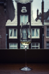 A glass of champagne on the windowsill with a view of traditional Dutch house.