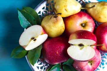 ripe apples and yellow pears lie in a plate on the table