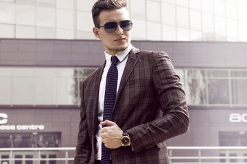 man businessman in sunglasses jacket and tie against the background of urban landscape