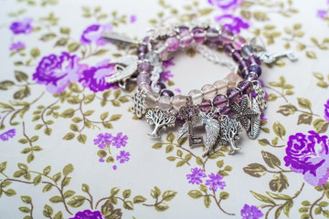 silver bracelet with natural stones, shaped beads and crystals on a purple textile background