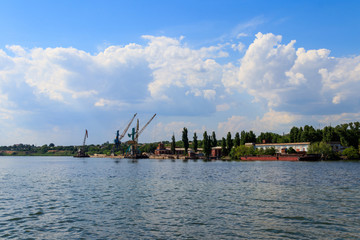 Heavy cranes in cargo port on the riverbank