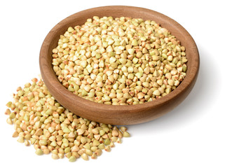 uncooked buckwheat in the wooden plate, isolated on the white background