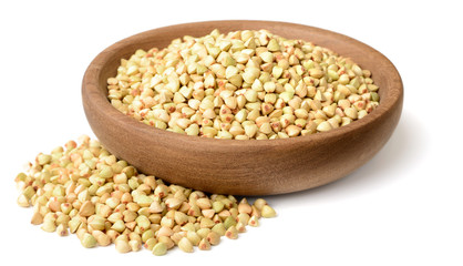 uncooked buckwheat in the wooden plate, isolated on the white background