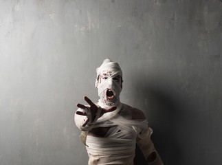 Terrorific mummy screaming on textured wall background.  Halloween holidays
