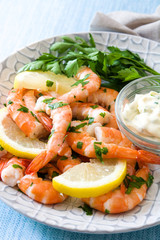 Grilled shrimps, parsley and lemon on blue wooden table. Close up