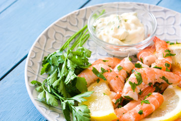 Grilled shrimps, parsley and lemon on blue wooden table. Close up