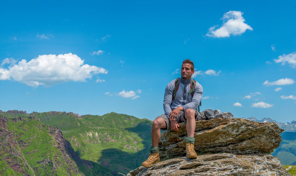 Young Man Hiker Sitting On A Rock In Mountain