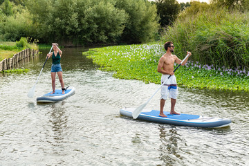 Man and woman stand up paddleboarding