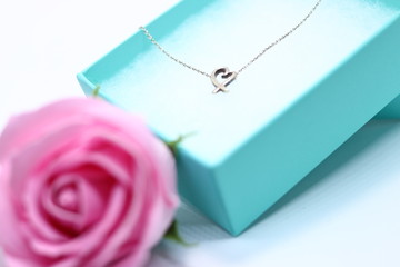 プレゼントの箱に入ったハートのネックレスと薔薇