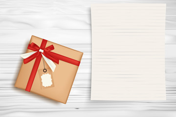 Christmas gift box and blank note paper on white wooden table.
