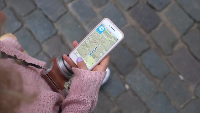 Female Traveler Using Map In GPS Navigation App On Smartphone
