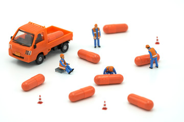 Miniature people Construction worker Load up the car model orange capsule medicine. on white background using as background business concept and Health concept with copy space.