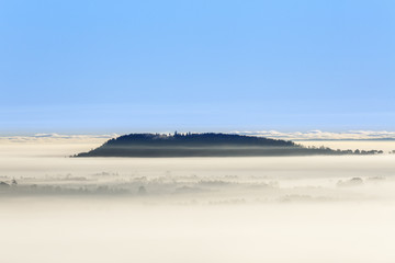 Foggy morning view with a mountain above the fog