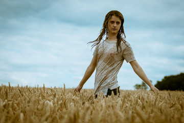 Young blond girl with wet hair and tshirt playing in a cornfield