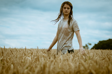 Young blond girl with wet hair and tshirt playing in a cornfield