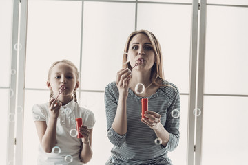 Mother and Little Daughter Blowing Soap Bubbles
