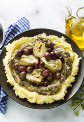 two plates with mashed potatoes, baba ganush, artichokes in oil and olives on the table. healthy vegan cuisine