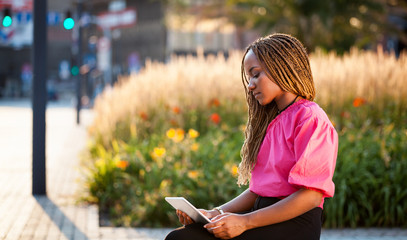 Beautiful African girl using tablet at city street
