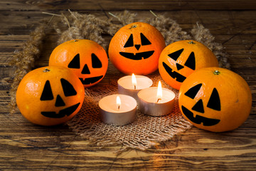 Painted funny faces on tangerines around lighted candles for Halloween