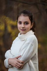 Portrait of beautiful tennage girl standing and posing in autumn park or forest. Natural light.