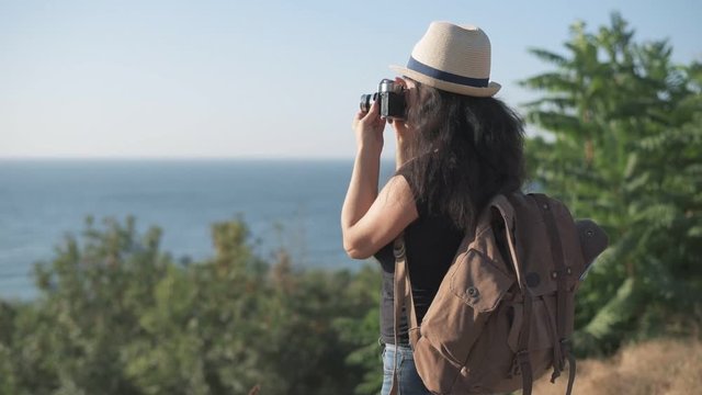 Cinemagraph- Happy female tourist with backpack. Woman making pictures with a retro camera while traveling . Motion Photo.
