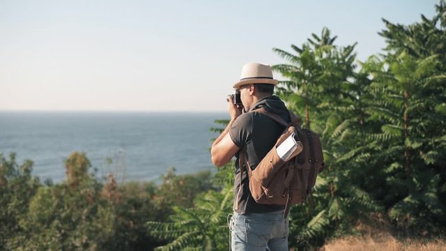 Cinemagraph- Happy male tourist with backpack. Man making pictures with a retro camera while traveling . Motion Photo.