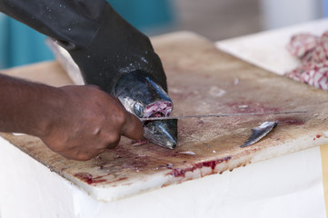 A fisherman carving his freshly caught fish at the market