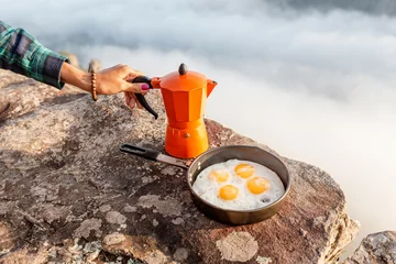 Tableaux sur verre Oeufs sur le plat breakfast meal Fried eggs in pan and coffee geyser maker outdoors in mountains, camping food concept